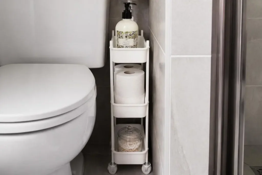 Best Extra Bathroom Storage for Apartments 8 A slim white rolling storage cart fitted into the narrow gap between a toilet and a tiled bathroom wall in a small apartment