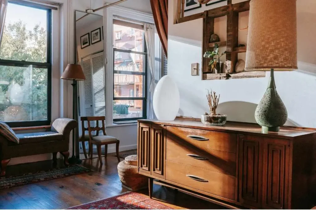 Styled dresser vignette with lamp, mirror, and decor in a small apartment