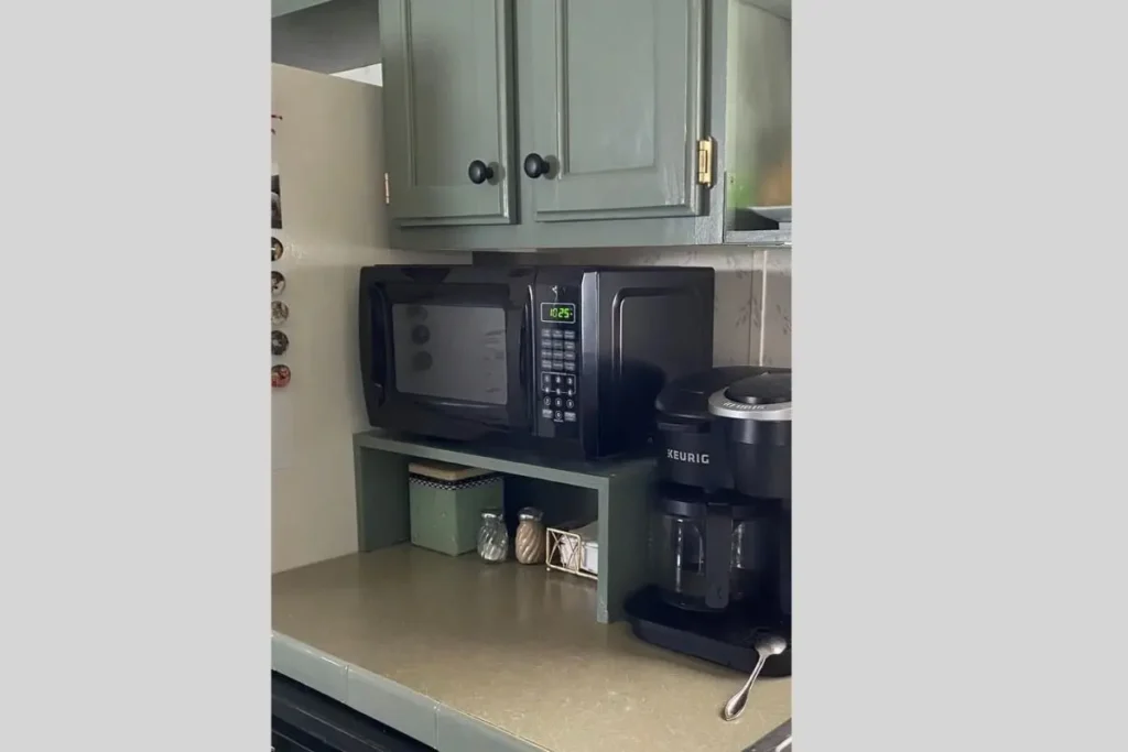 Where to put a microwave in a small kitchen with no counter space? 1 A compact black microwave on a wooden shelf to solve where to put microwave in small kitchen with no counter space.