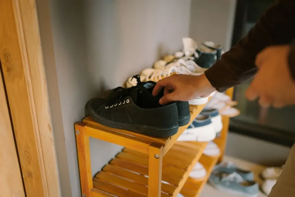 Wooden slim shoe rack holding shoes in a small entryway.