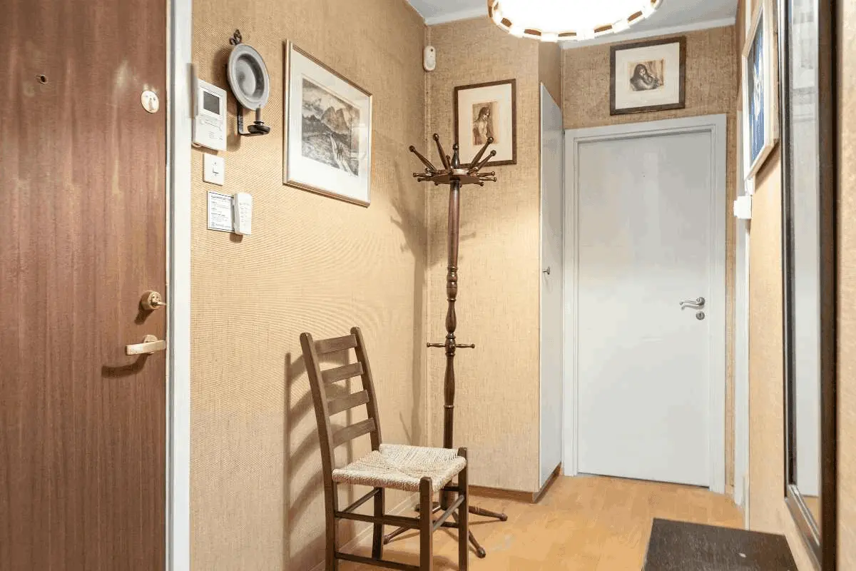 Small foyer Foyer Decorating Ideas featuring a narrow wooden chair and coat rack with warm lighting.