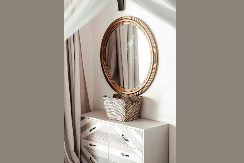round decorative wall mirror above entryway storage console cabinet.