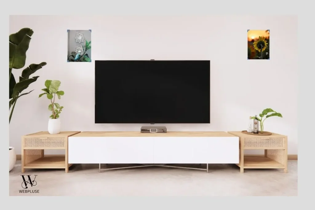 5 Small Living Room Decor Ideas Without TV Wall Mount 2 standing television on white low console surrounded by framed art and indoor plants.