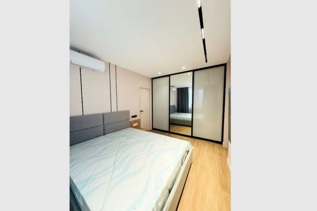 Should Wardrobe Match Bedroom Furniture? 7 Small Room Rules 5 small bedroom wardrobe layout with mirrored sliding doors reflecting bed frame.